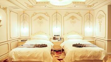 A hotel room with two beds, a chandelier, and ornate wall decorations.