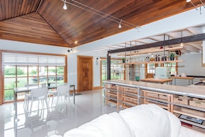 A modern kitchen with wooden cabinets, a built-in island, and a dining area with a glass table and chairs.