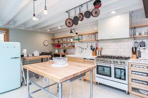 A modern kitchen with a wooden table, white cabinets, and a stove.