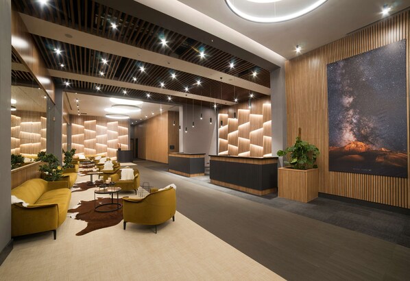 A modern lobby with sofas, a reception desk, and a large wall mural.