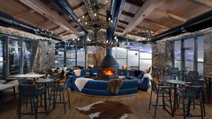 A cozy interior with a stone wall, a fireplace, and a blue sofa surrounded by tables and chairs. - Radisson Blu Hotel, Mount Erciyes (Kayseri)