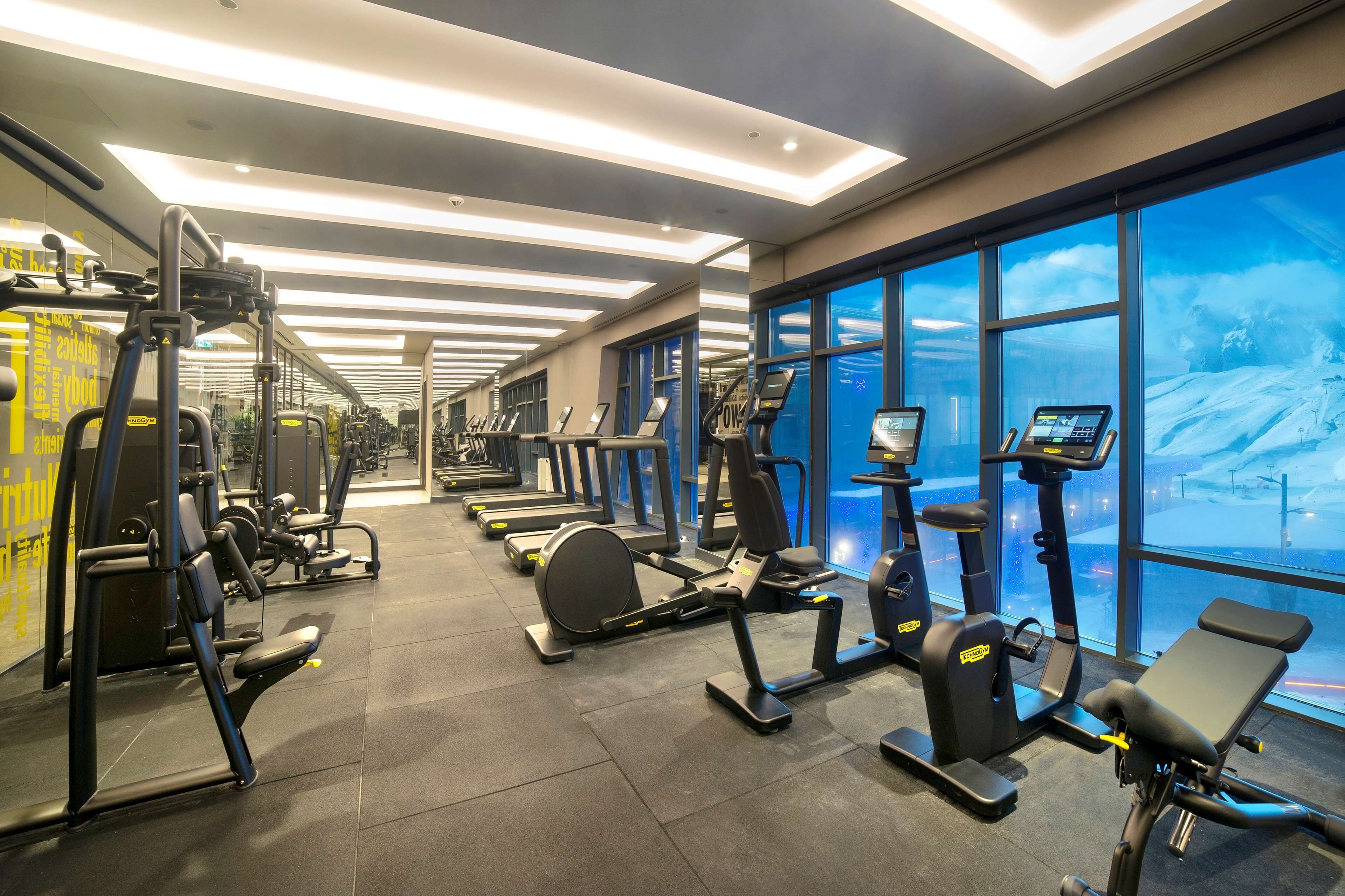 Une salle de sport équipée de tapis de course, de vélos elliptiques et de matériel de musculation.