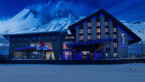 A hotel with a modern design, featuring a prominent entrance and a mountain backdrop. - Radisson Blu Hotel, Mount Erciyes (Kayseri)