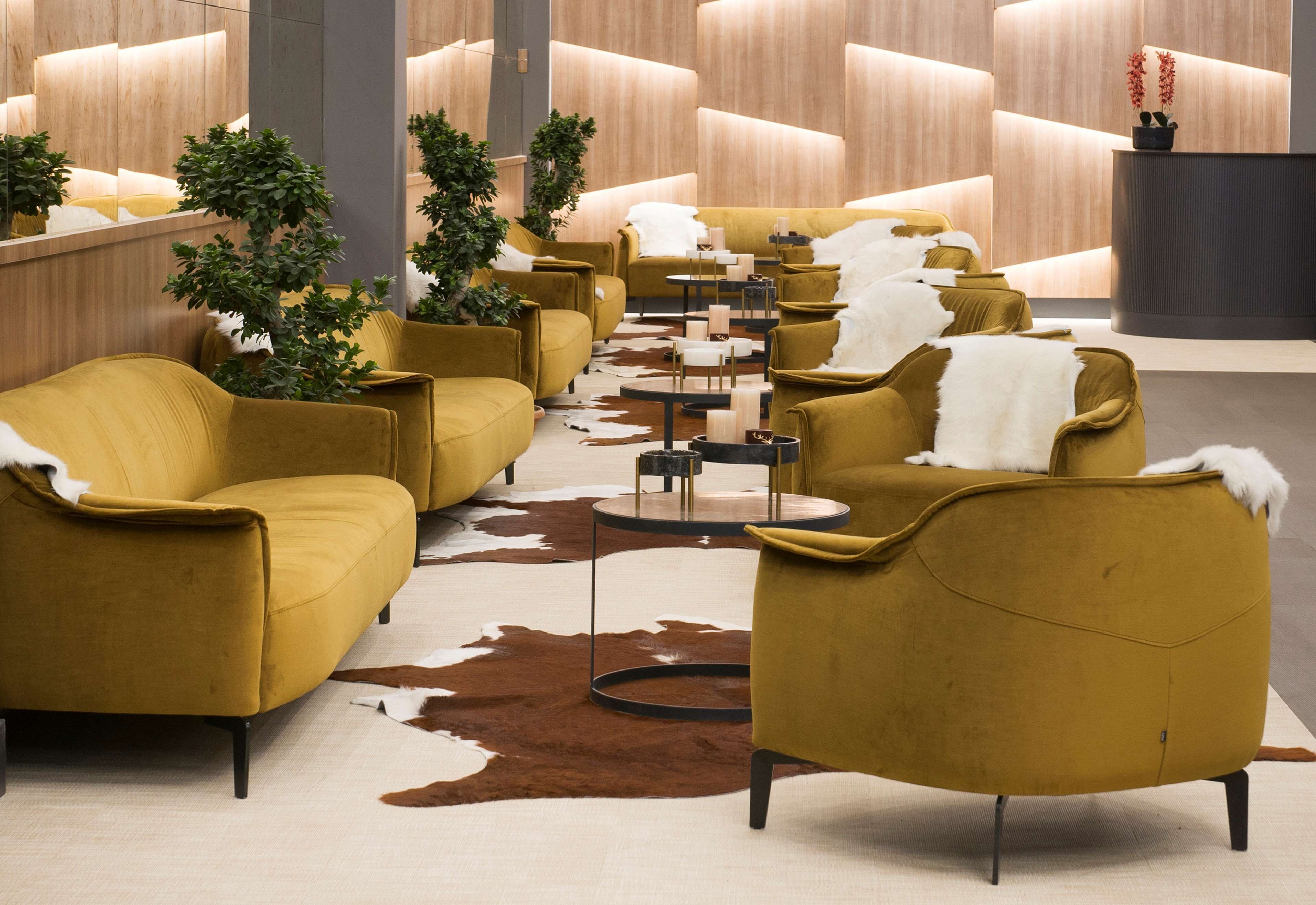 A modern lobby with yellow armchairs, a cowhide rug, and a reception desk.