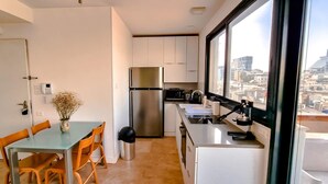 A compact kitchen with white cabinets, a stainless steel refrigerator, and a window overlooking a cityscape. - Apt Ophrys 1BR Tel Aviv Kalisher St TL66 (Tel Aviv)