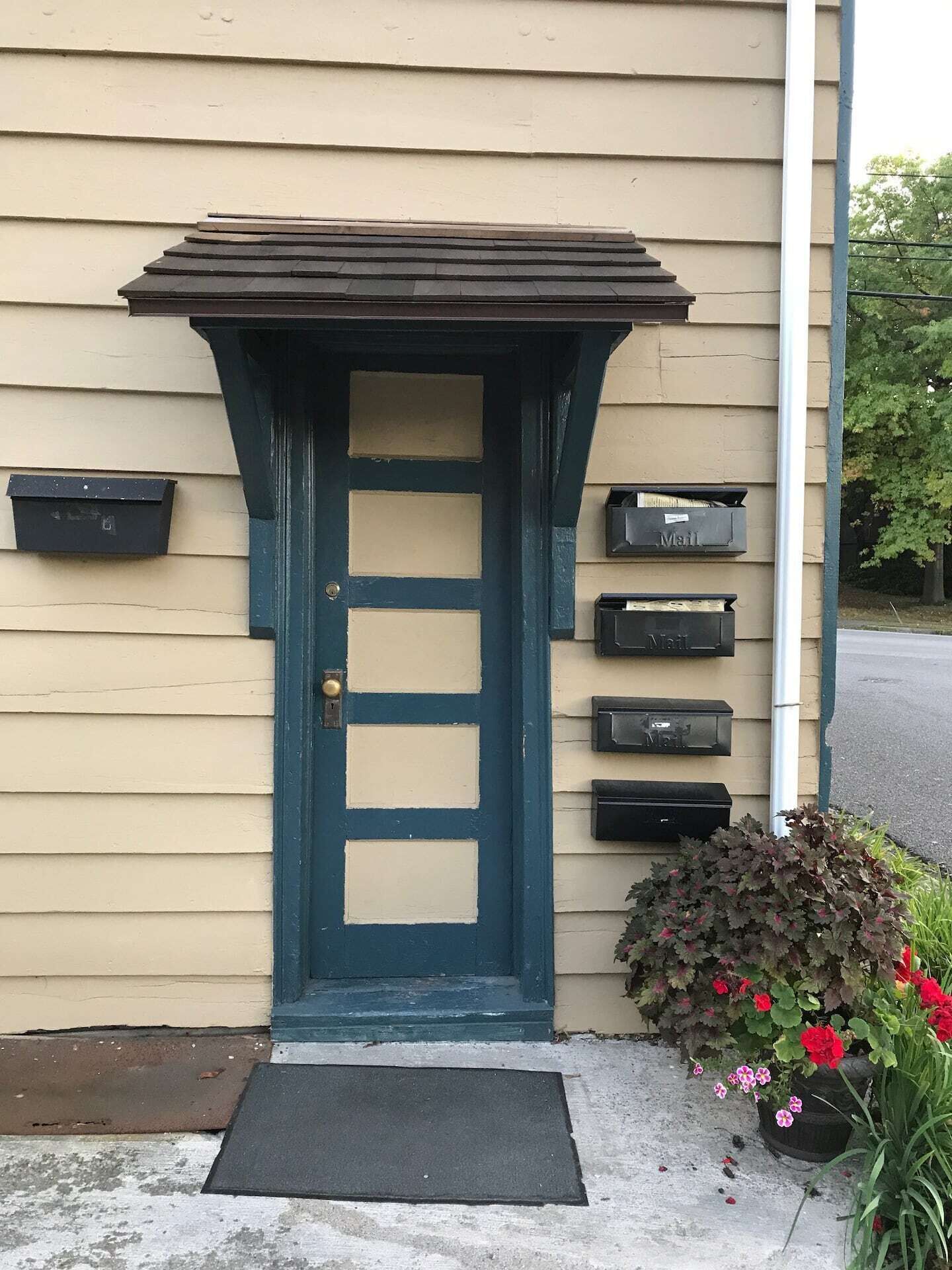 A blue door with a small porch and mailboxes on the side.