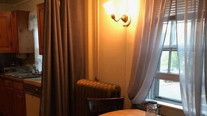 Cozinha acolhedora com armários de madeira, uma mesa de jantar com cadeiras e uma janela com cortinas.