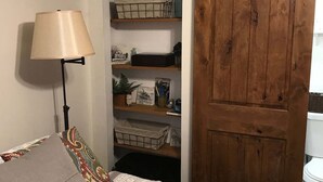 Quarto com cama, mesa de cabeceira, luminária, guarda-roupa e estante.