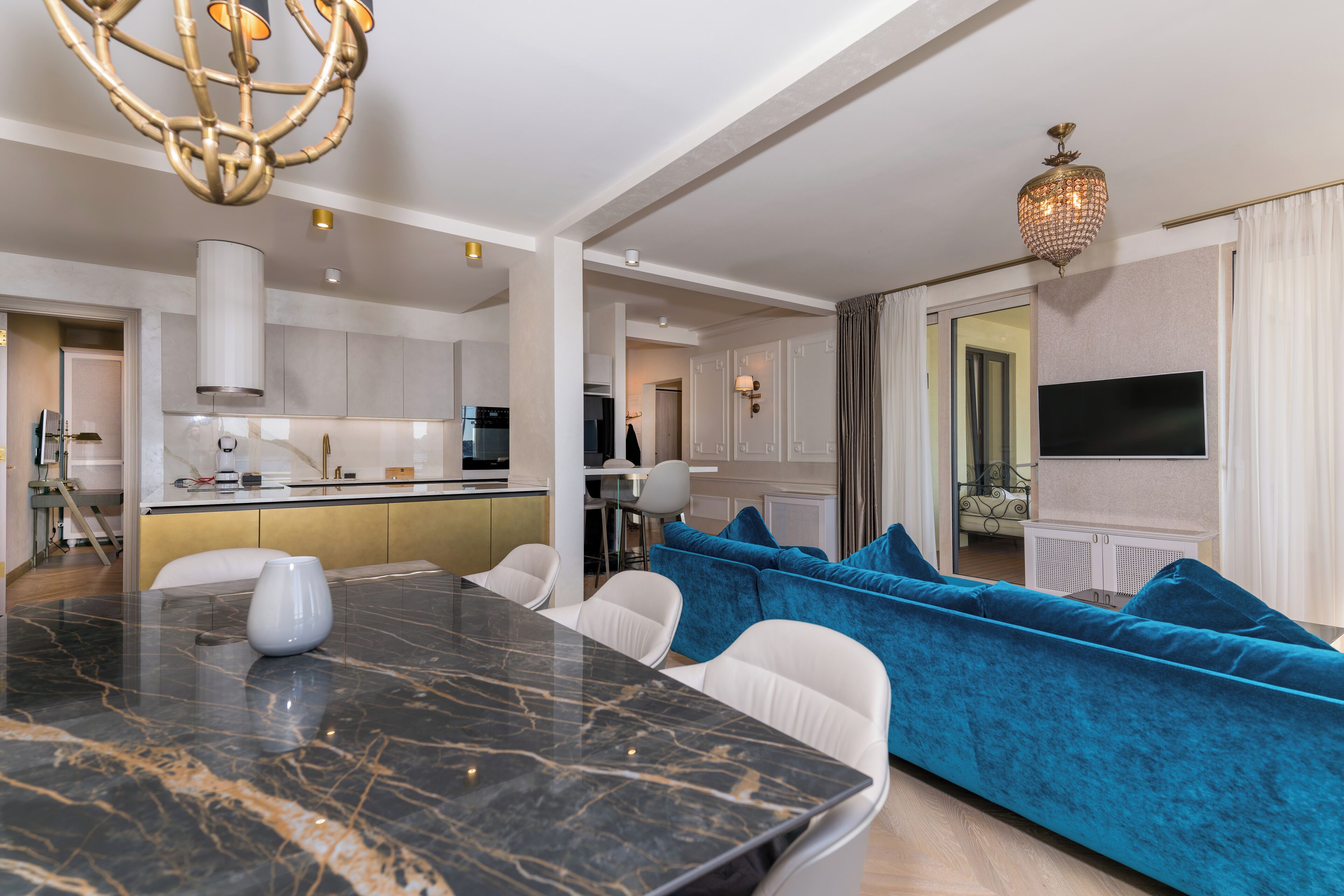 A modern living room with a marble dining table, a blue sofa, and a TV mounted on the wall.