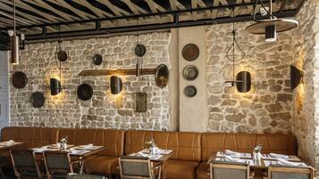 A restaurant with stone walls, leather seating, and pendant lighting.