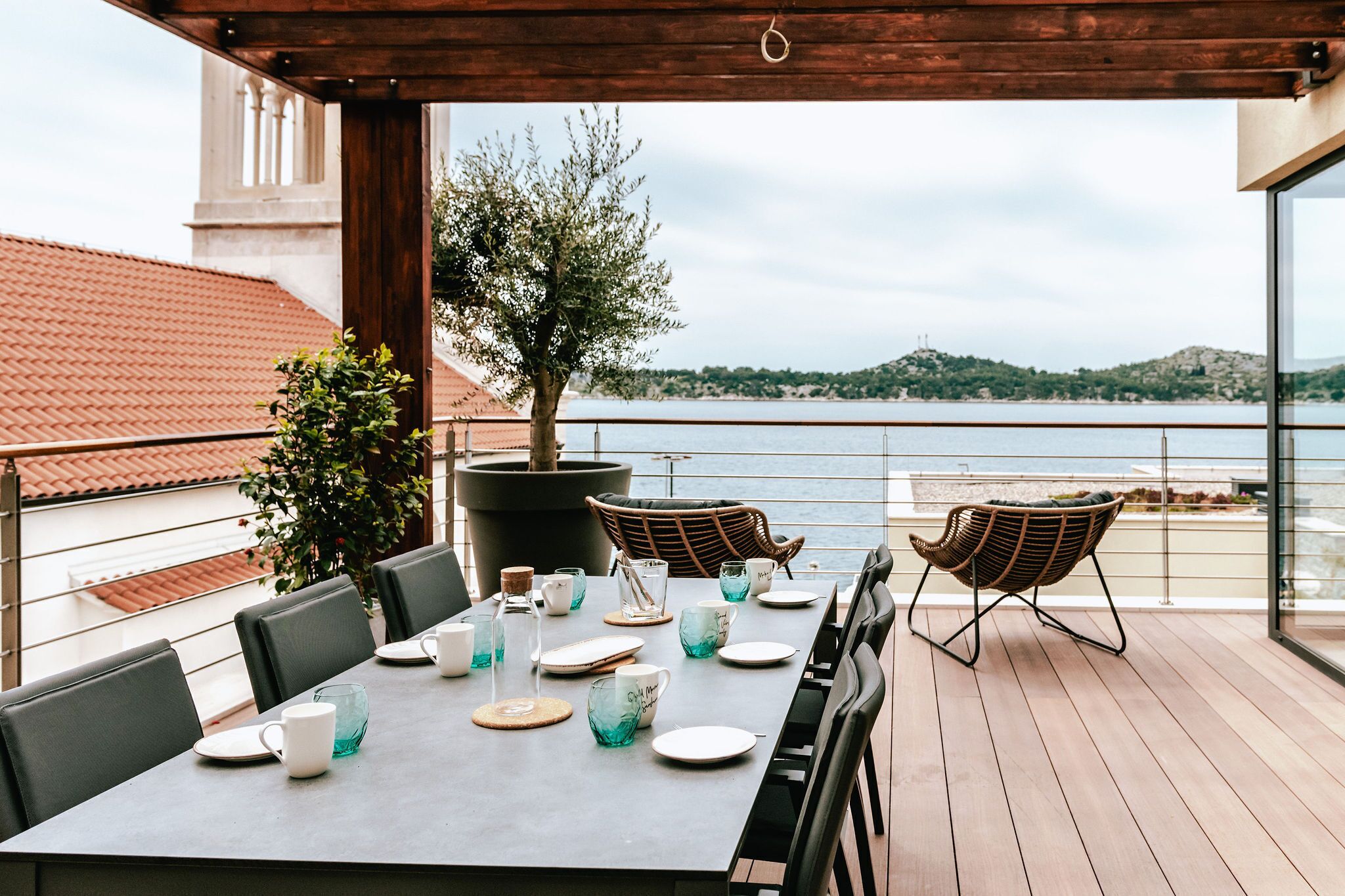 En terrasse med et spisebord, med udsigt over vand og bakker.