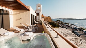 A balcony with a hot tub, lounge chairs, and a view of the sea. - Armerun Heritage Hotel (Sibenik)