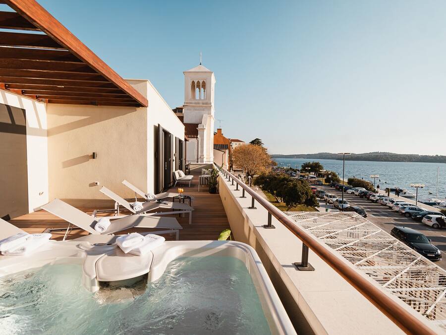 Un balcon avec un jacuzzi, des chaises longues et une vue sur la mer.
