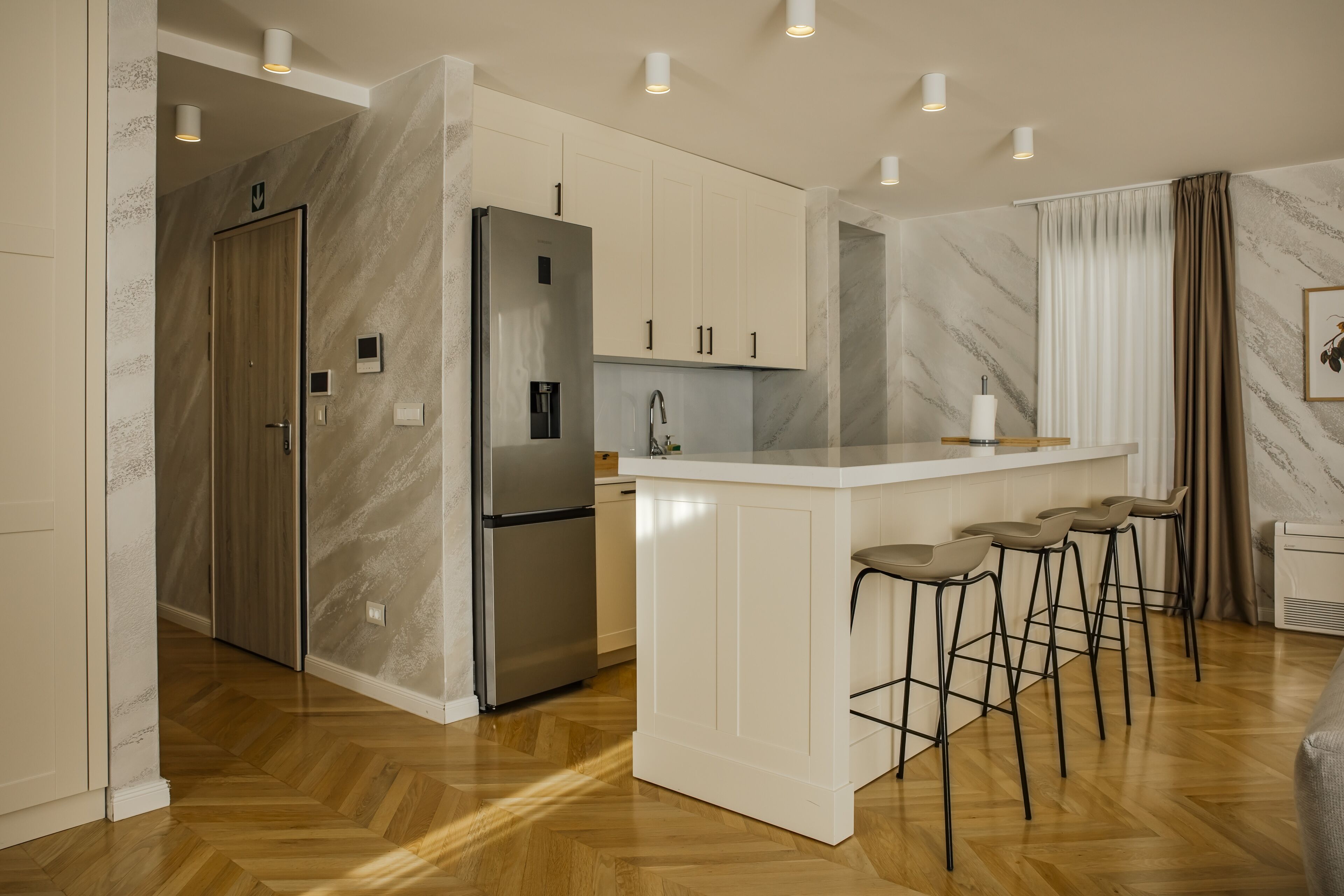 Una cocina moderna con salpicadero de mármol, electrodomésticos de acero inoxidable y una isla central con taburetes de bar.