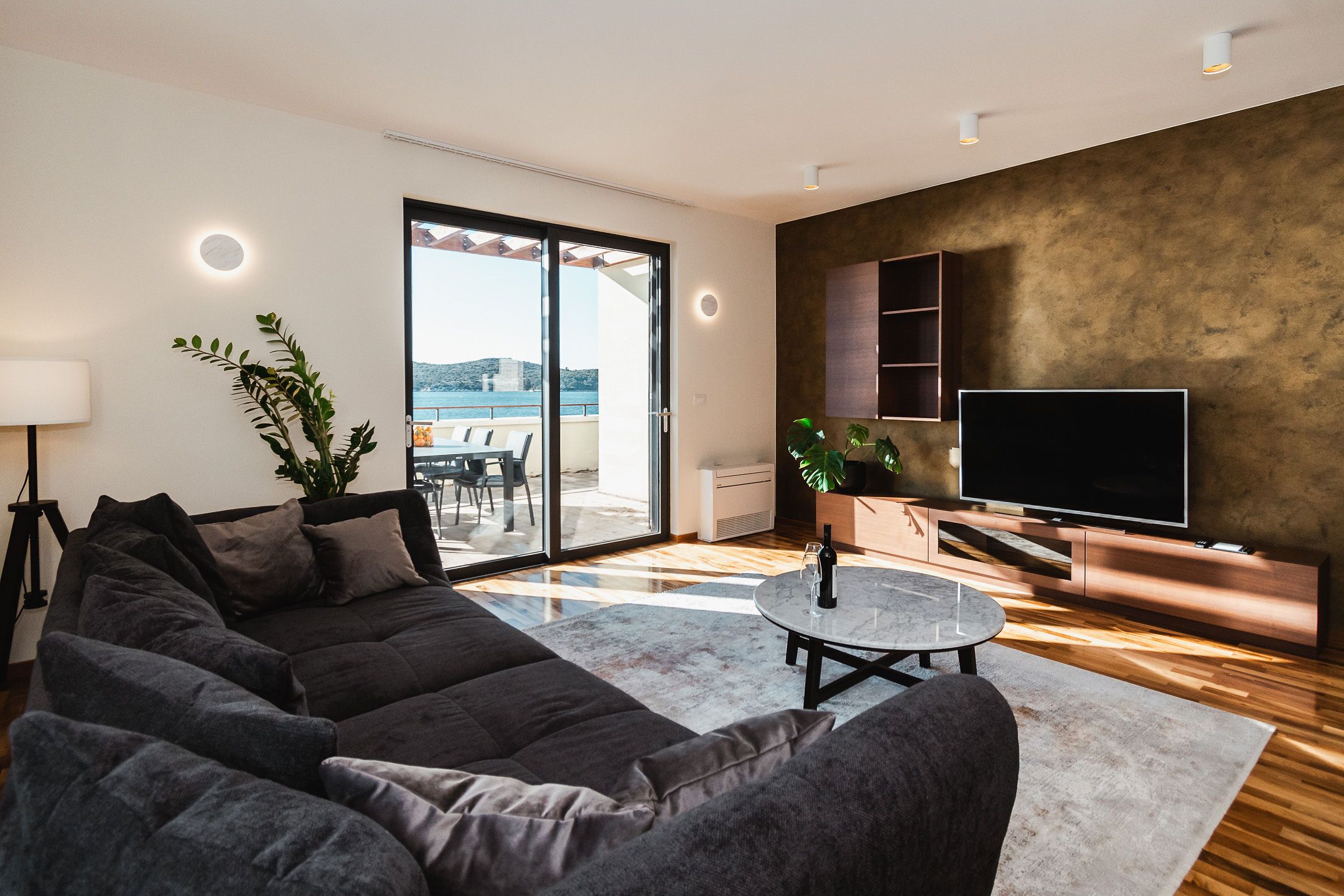 A modern living room with a large sofa, a flat-screen TV, and a dining area with a table and chairs.