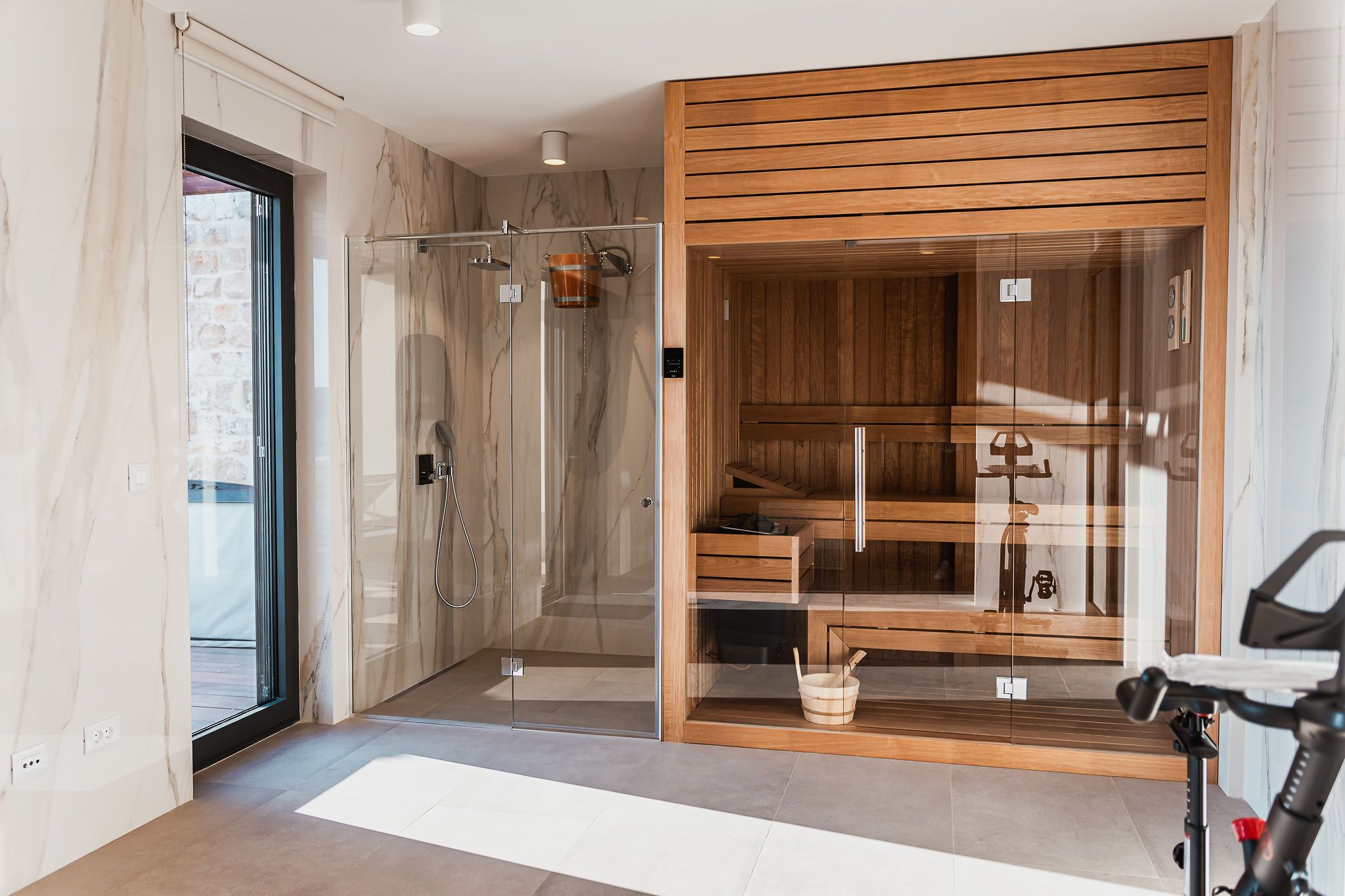 A modern bathroom with a glass shower enclosure, wooden cabinets, and a visible towel rack.