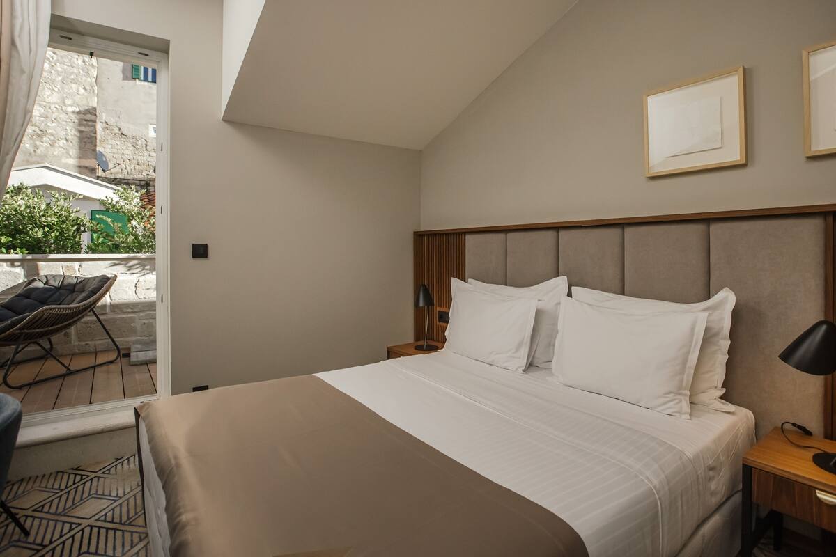 Une chambre d’hôtel avec un lit, une table de chevet, une chaise et une vue sur l’extérieur.
