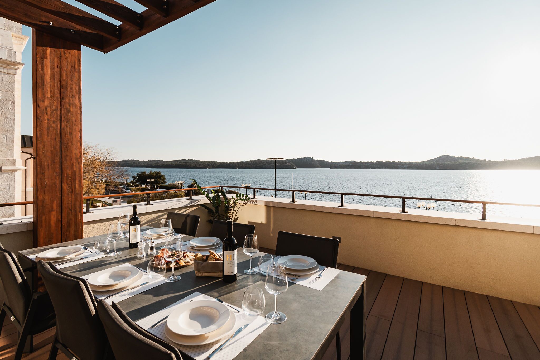 A dining table set for two with a view of a lake and hills in the background.