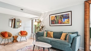 A living room with a teal sofa, two armchairs, a coffee table, and a colorful rug. - Spacious Family or Couples Condo - Walk to Coligny Beach & Shops (Hilton Head Island)