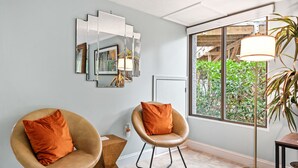 A modern room with two leather chairs, a floor lamp, and a large window with a view of greenery. - Spacious Family or Couples Condo - Walk to Coligny Beach & Shops (Hilton Head Island)