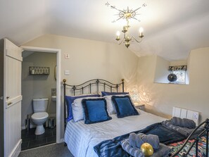 A bedroom with a bed, a chandelier, a window, and a bathroom visible through an open door. - 3 bedroom accommodation in Llanfair Caereinion (Llanfair Caereinion)