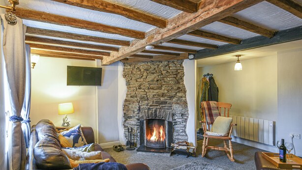 Ein gemütliches Wohnzimmer mit Kamin aus Stein, Ledersofa und Holzstuhl.
