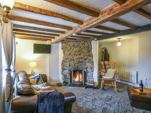 A cozy living room with a stone fireplace, leather sofa, and a wooden chair. - 3 bedroom accommodation in Llanfair Caereinion (Llanfair Caereinion)