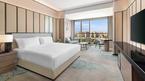 A modern hotel room with a large bed, a desk, a chair, a TV, and a view of the city. - Holiday Inn Shanghai Minhang Center by IHG (Shanghai)
