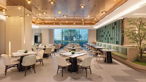 A modern dining area with round tables, chairs, and pendant lighting. - Holiday Inn Shanghai Minhang Center by IHG (Shanghai)
