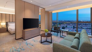 A modern hotel room with a large TV, comfortable seating, a bed, and a city view. - Holiday Inn Shanghai Minhang Center by IHG (Shanghai)