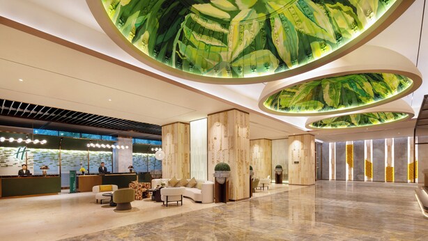 A modern hotel lobby with a reception desk, seating area, and a unique ceiling design. - Holiday Inn Shanghai Minhang Center by IHG (Shanghai)