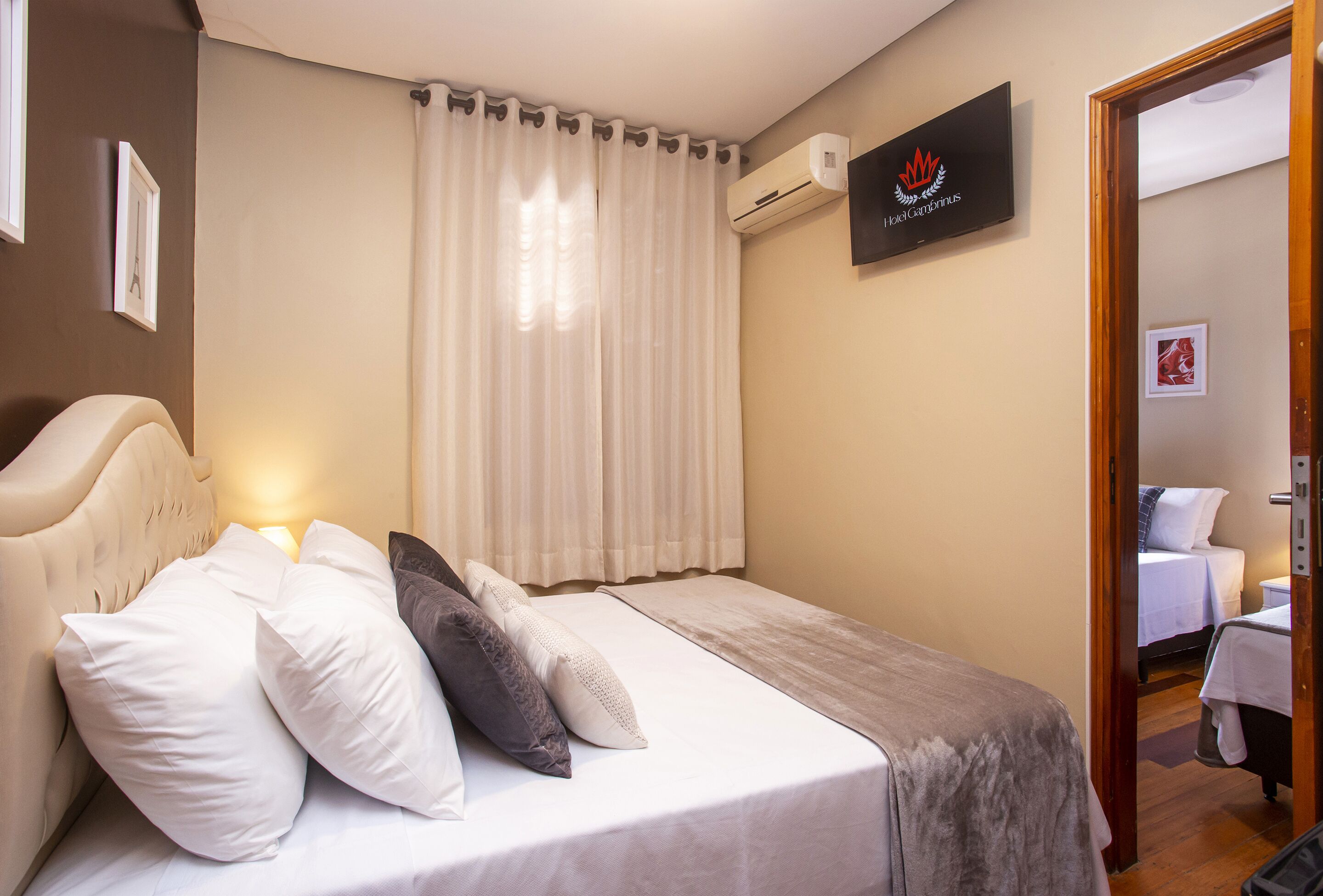 A neatly made bed with white and gray bedding, a headboard, and a bedside lamp.