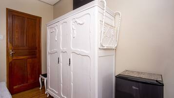 Una habitación con una puerta de madera, un armario blanco y un electrodoméstico negro.
