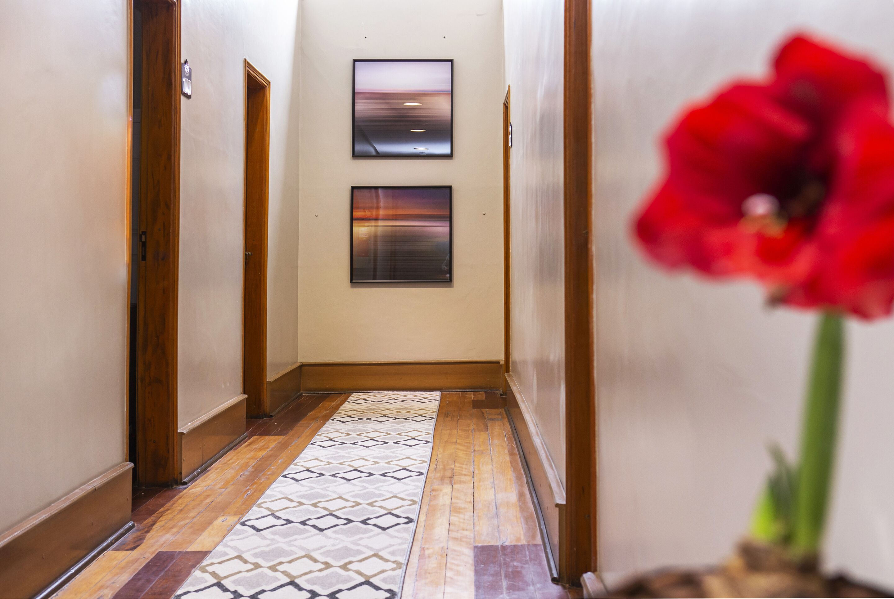 A hallway with wooden doors, a patterned floor, and two framed pictures on the wall.