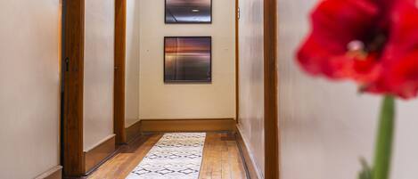 A hallway with wooden doors, a patterned floor, and two framed pictures on the wall.