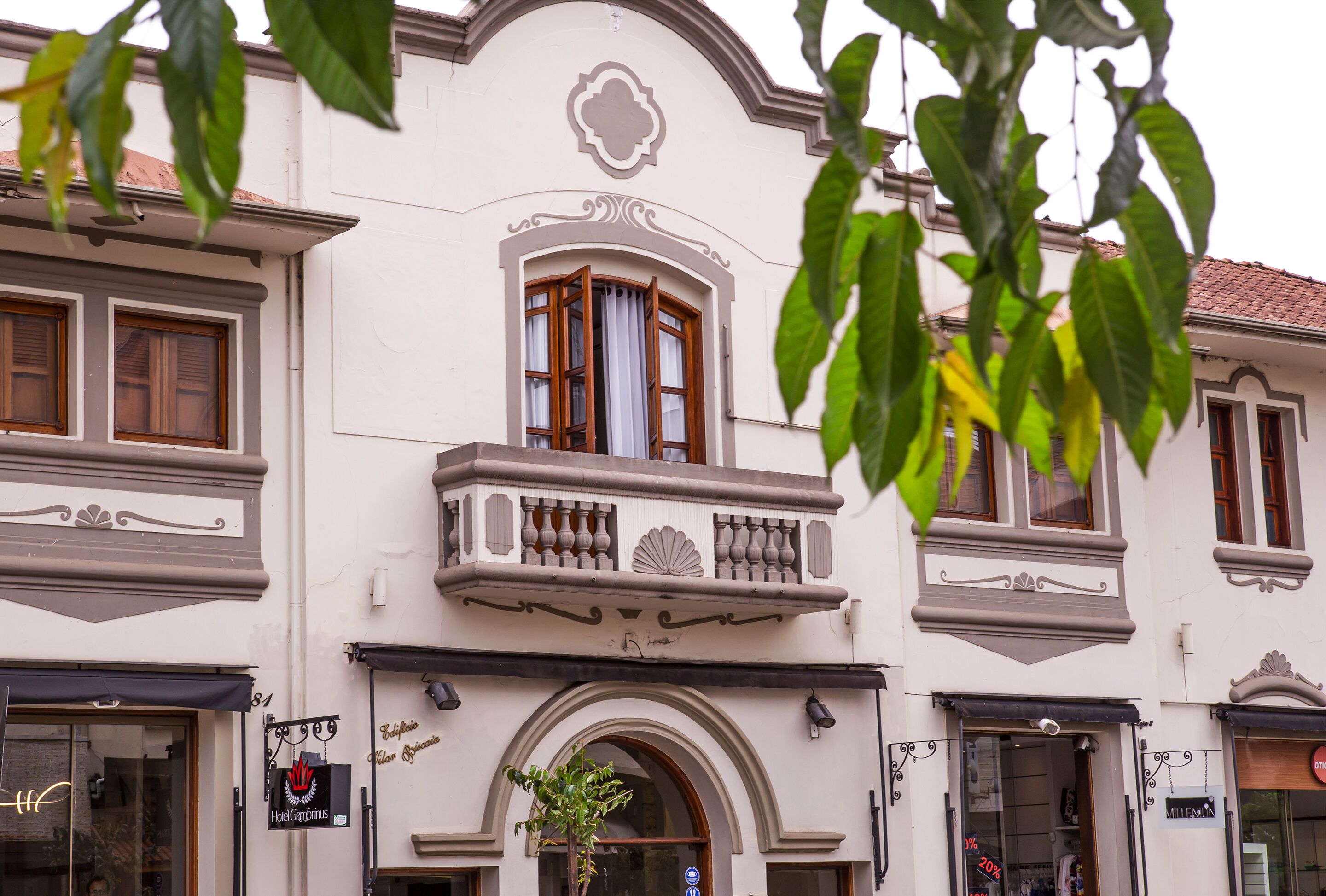 A building with a balcony, a shop on the ground floor, and a sign for Hotel Carminum.