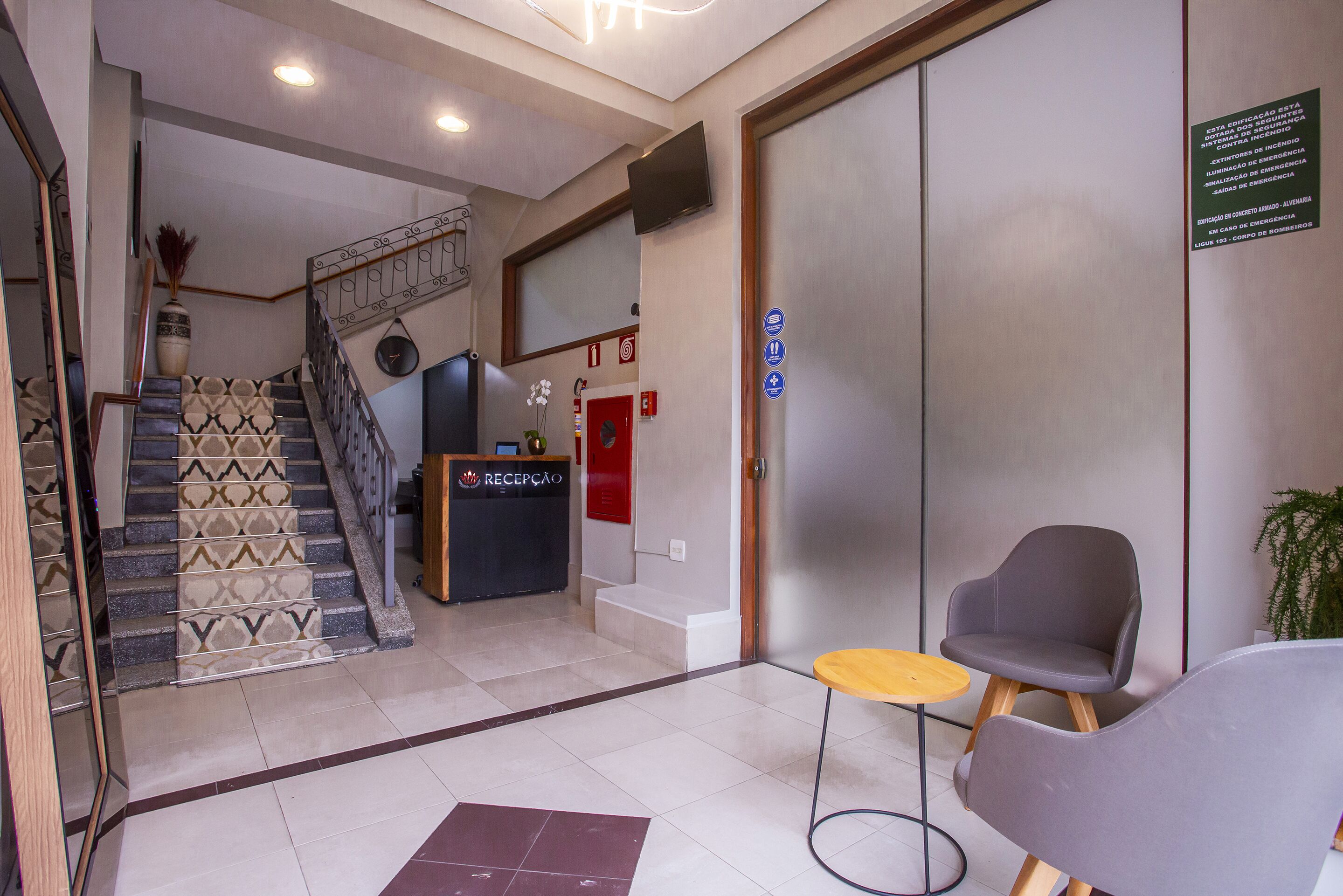 A reception area with a staircase, a reception desk, and a seating area with a small round table.