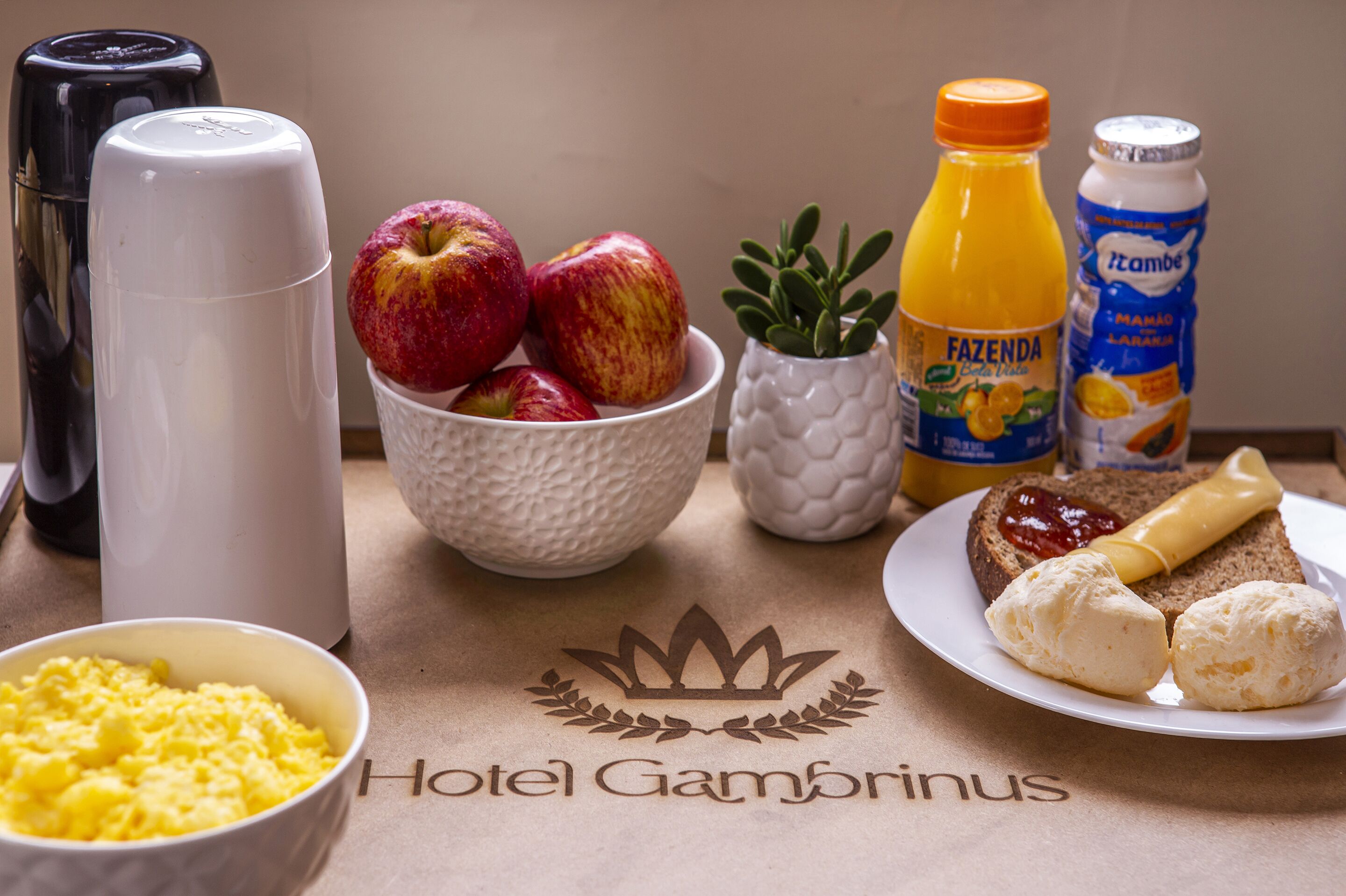 A breakfast setting with scrambled eggs, apples, orange juice, and a plate with toast and butter.