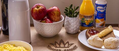 A breakfast setting with scrambled eggs, apples, orange juice, and a plate with toast and butter.
