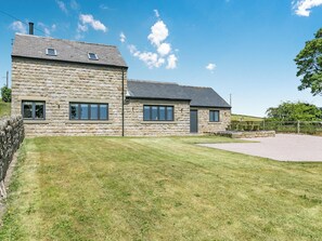 A stone building with a sloped roof, multiple windows, and a paved driveway. - 3 bedroom accommodation in Barlow, near Chesterfield (Barlow, near Chesterfield)