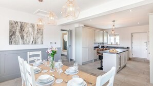 Una cocina moderna con armarios blancos, una isla central e iluminación colgante.
