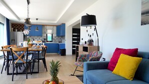 Een moderne woonkamer met een blauwe bank, kleurrijke kussens en een houten bijzettafeltje met fruit.
