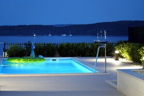 Une piscine avec vue sur une étendue d’eau et des bateaux au loin.