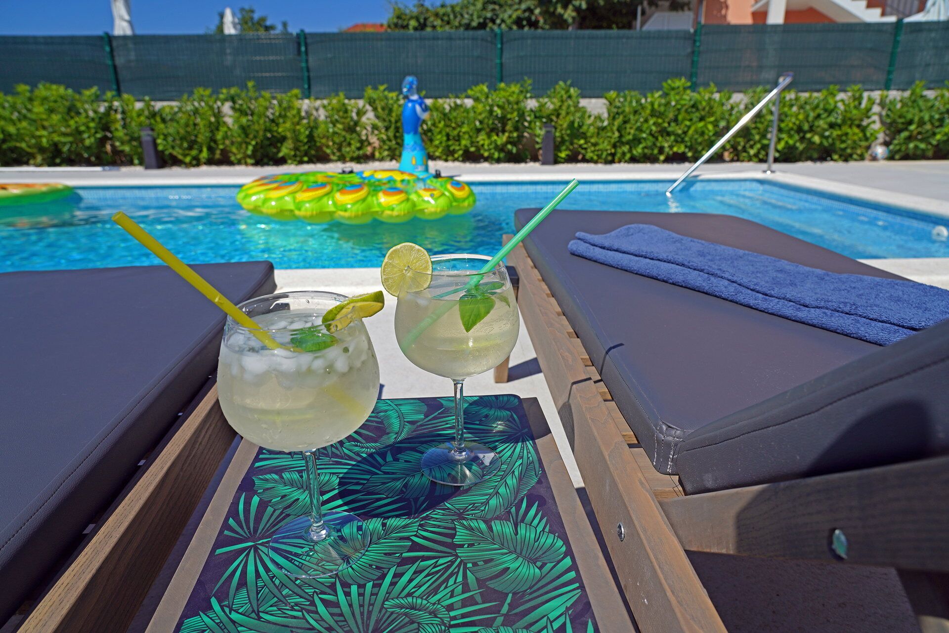 A poolside area with lounge chairs, a table with drinks, and a pool in the background.