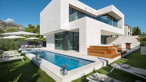 Ein modernes, zweistöckiges Haus mit Swimmingpool, Außenbereich und Whirlpool.
