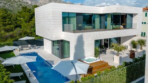 Ein modernes, zweistöckiges Haus mit Schwimmbad, Sitzgelegenheit im Freien und Whirlpool.