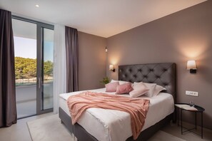 Un dormitorio moderno con una cama grande, un ventanal de vidrio que da a un balcón y dos lámparas fijadas a la pared.