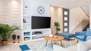 A modern living room with a flat-screen TV, a clock, and a staircase. - Beachfront Villa Charisma with Pool (Splitska)