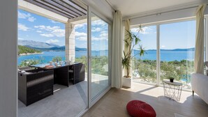 A modern room with a large sliding glass door leading to a balcony with a view of a lake and mountains. - Villa Auras with Heated Pool (Slano)