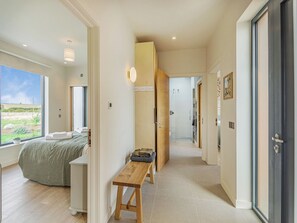 Een moderne hotelkamer met een groot raam, een bed, een houten bankje en een douche.